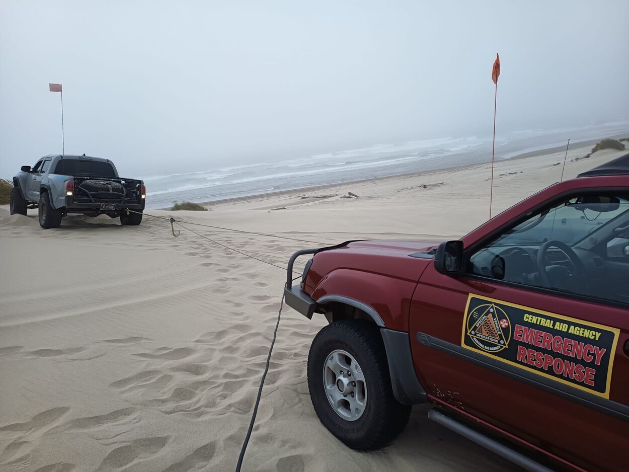 SVO vehicles winching out a stuck truck on the sand.