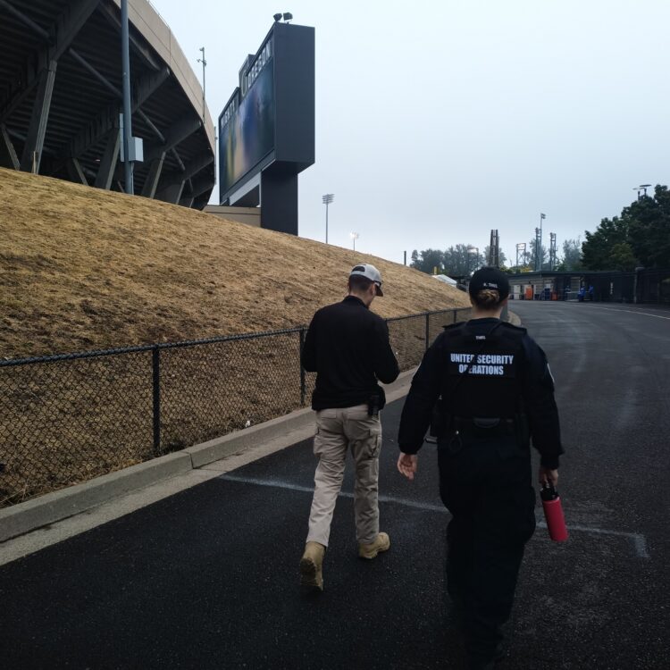Female USO Agent walks with a Duck Store Loss Prevention Officer during a UO Home Game at Autzen Stadium.